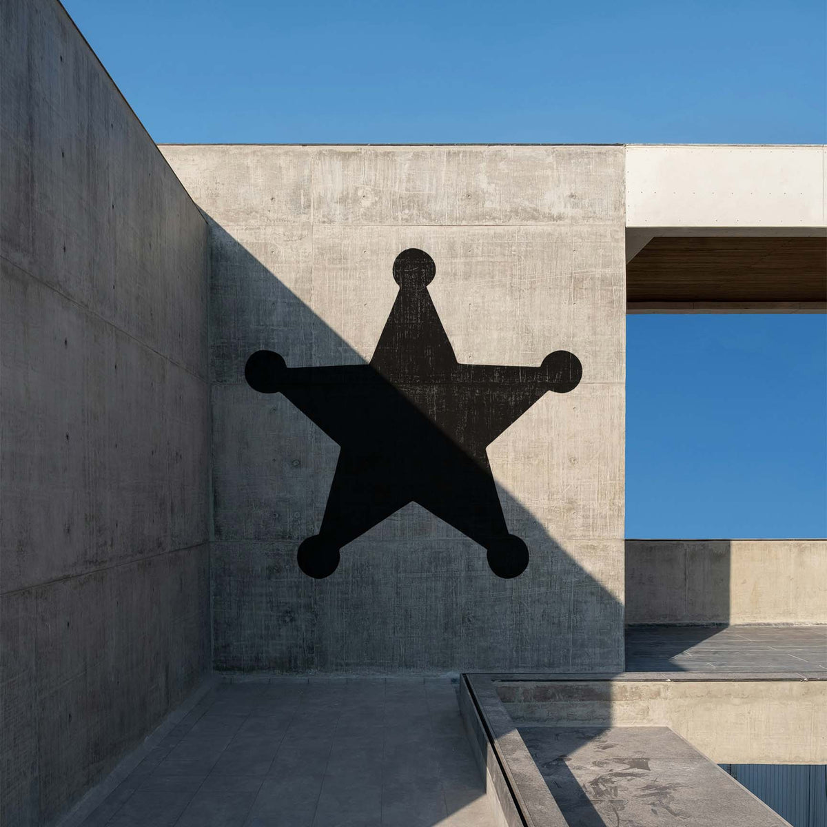 Sheriff Star Stencil makes a bold black statement across a sunlit modern concrete wall