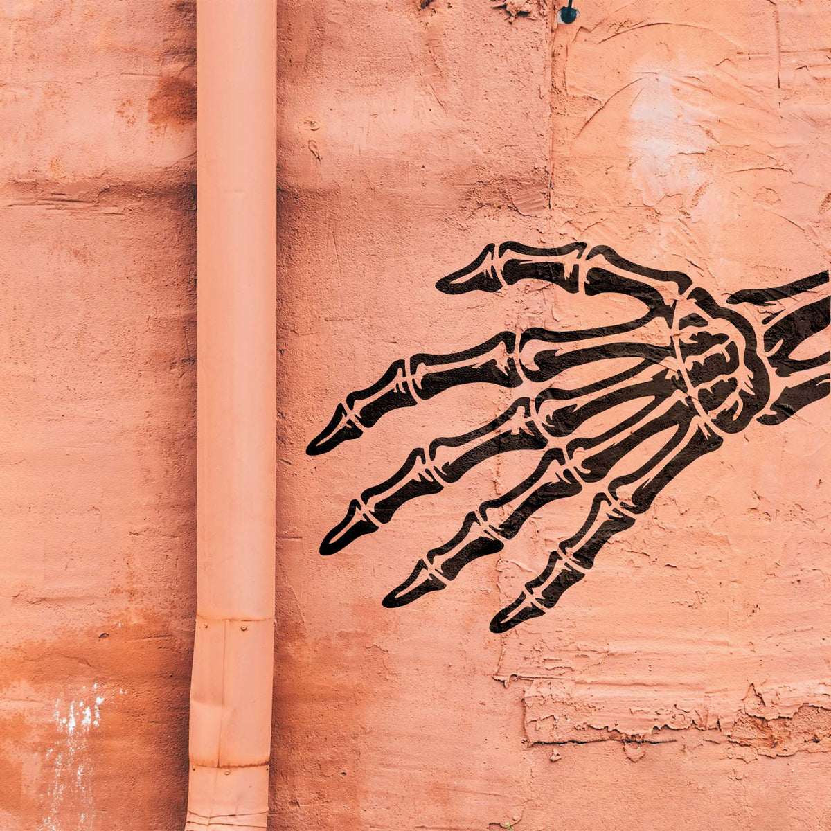 Oversized Skeleton Hand Bones Stencil reaches across a weathered salmon-colored wall