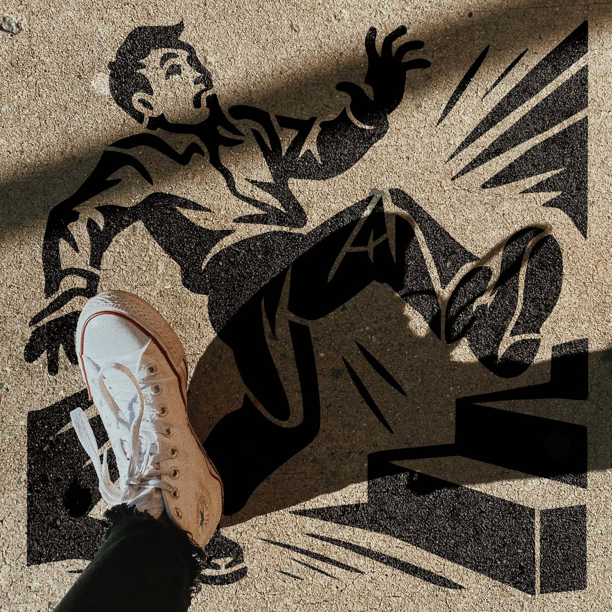 Slip Hazard Stencil shows a startled man stumbling near steps on a sunlit concrete walkway.
