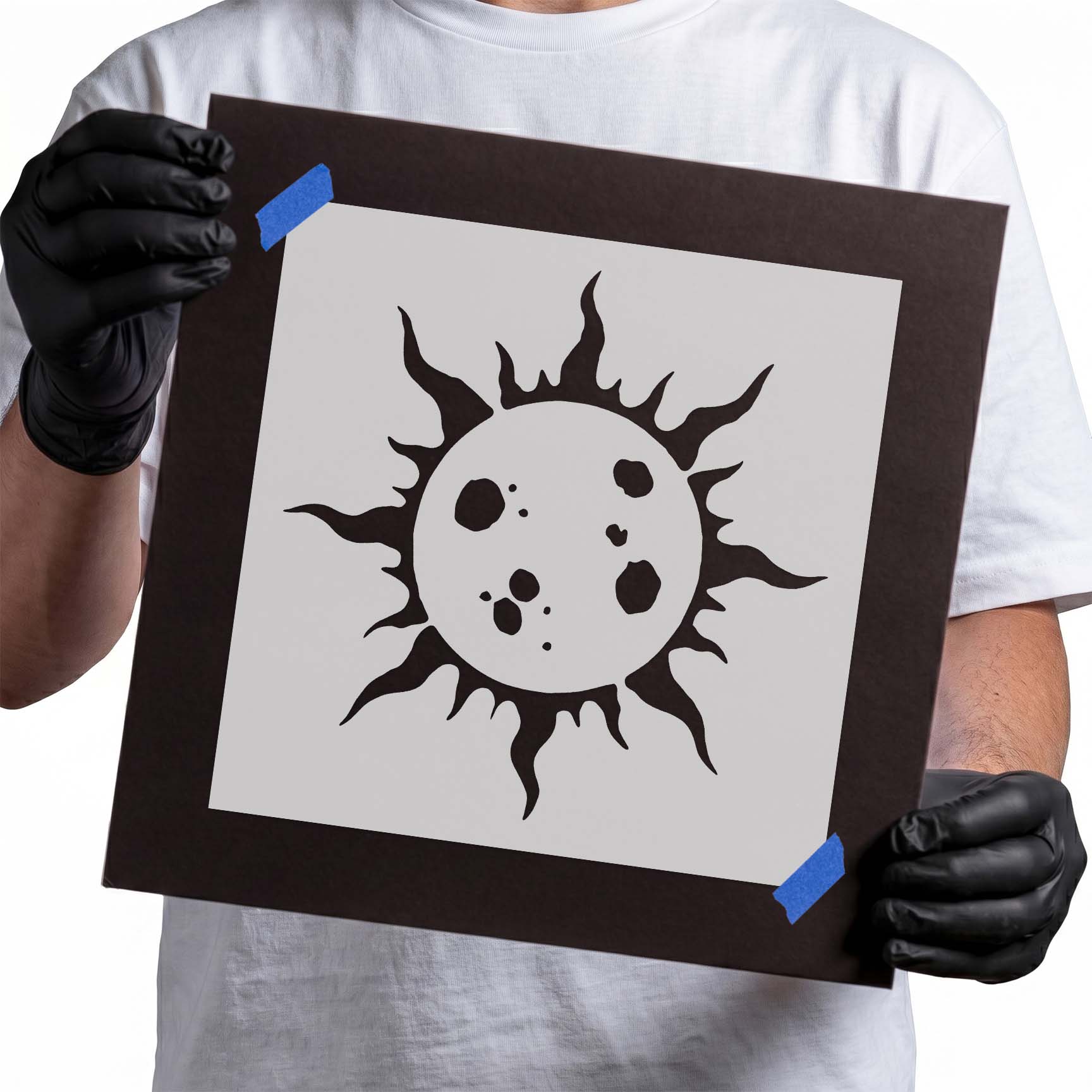 Gloved hands holding Solar Flare Stencil taped to black cardboard