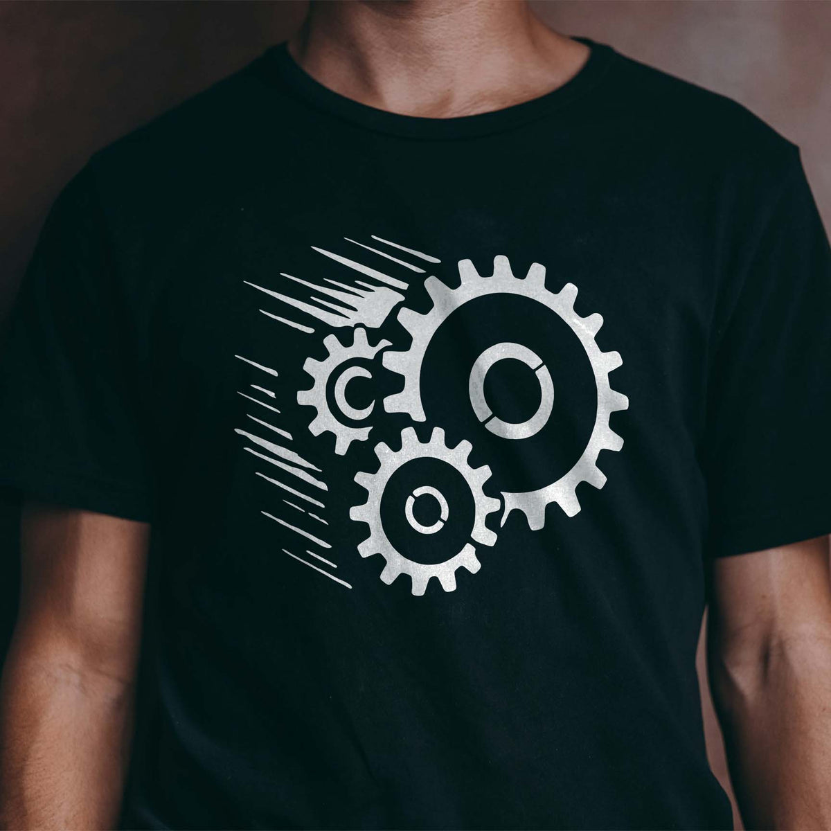 Speeding Gears Stencil printed in white across a black T-shirt with three moving cog designs.