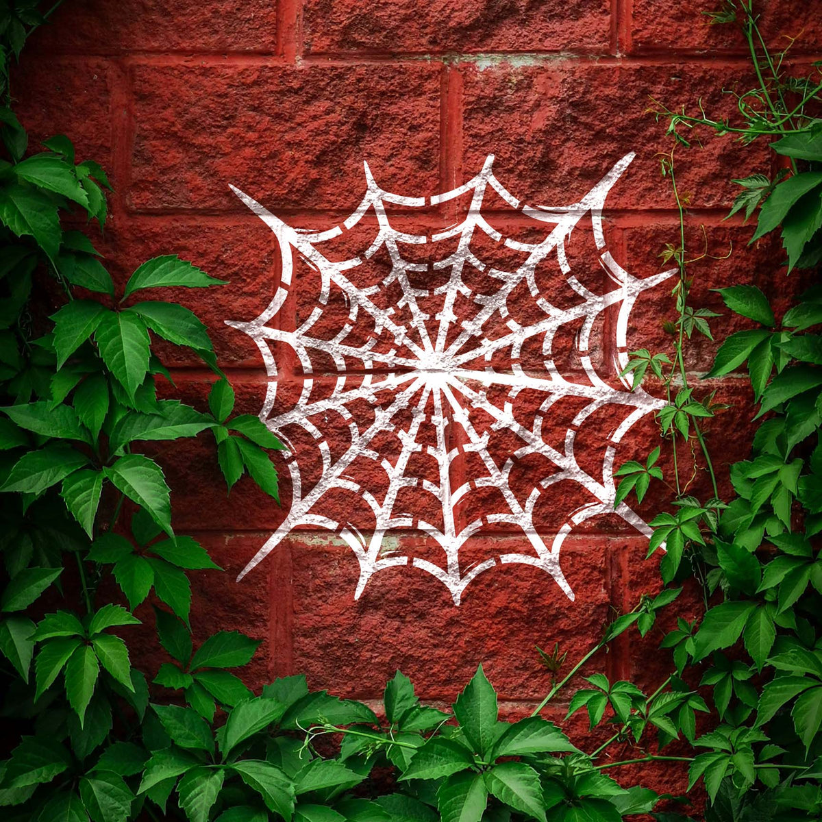 White Radial Spider Web Stencil creates a striking web pattern on an ivy-framed brick wall