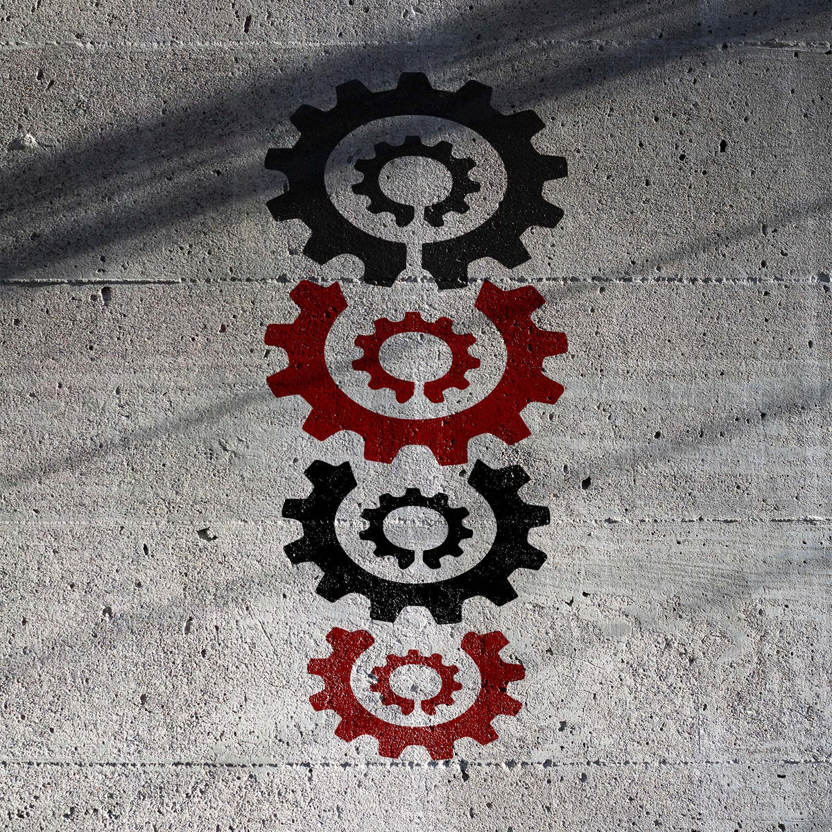 Stacked Gears stencil featuring four alternating black and red cogwheels on a textured concrete wall
