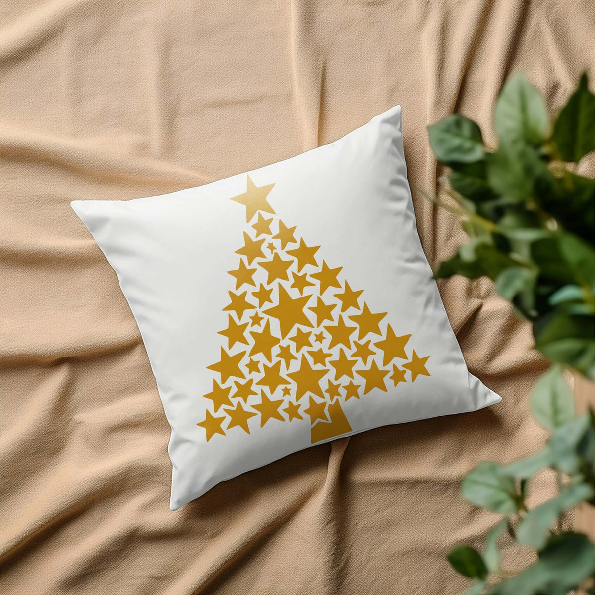 Starry Christmas Tree Stencil printed in gold on a white throw pillow over soft beige fabric.