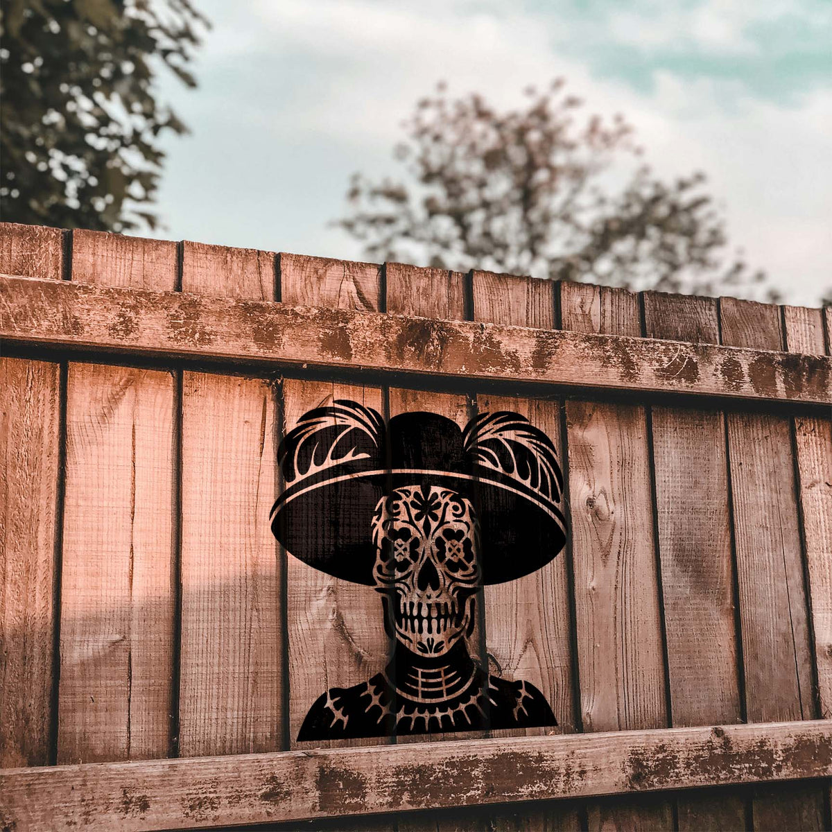 Sugar Skull Catrina Stencil stands out in black across a rustic wooden fence outdoors