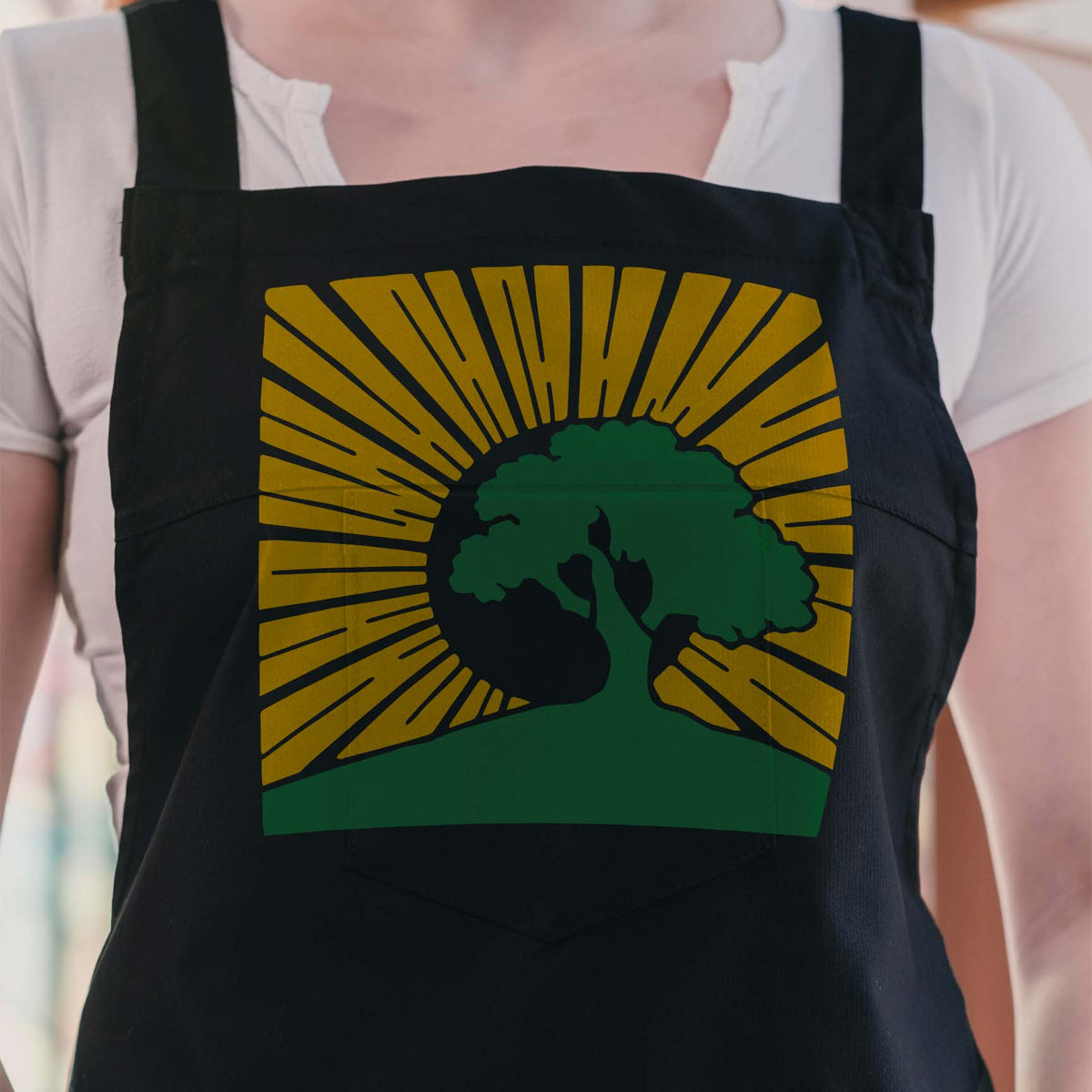 Golden rays frame a green tree on an apron featuring the Sunrise Tree Silhouette Stencil