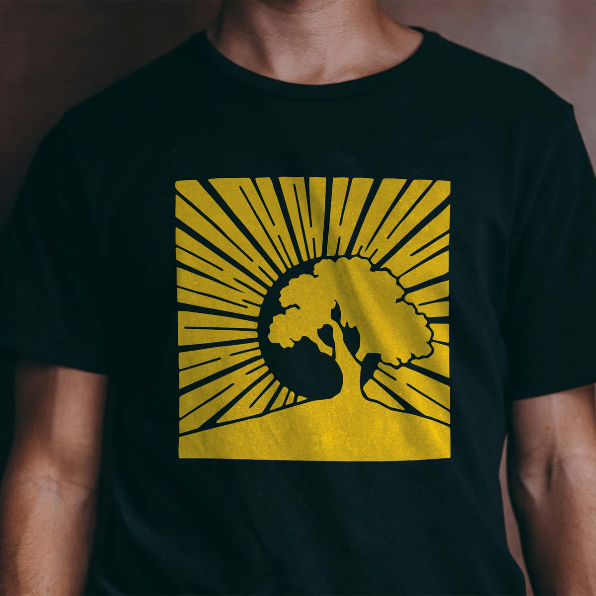 Golden Sunrise Tree Silhouette Stencil artwork stands out with radiant sunbeams on a black t-shirt.
