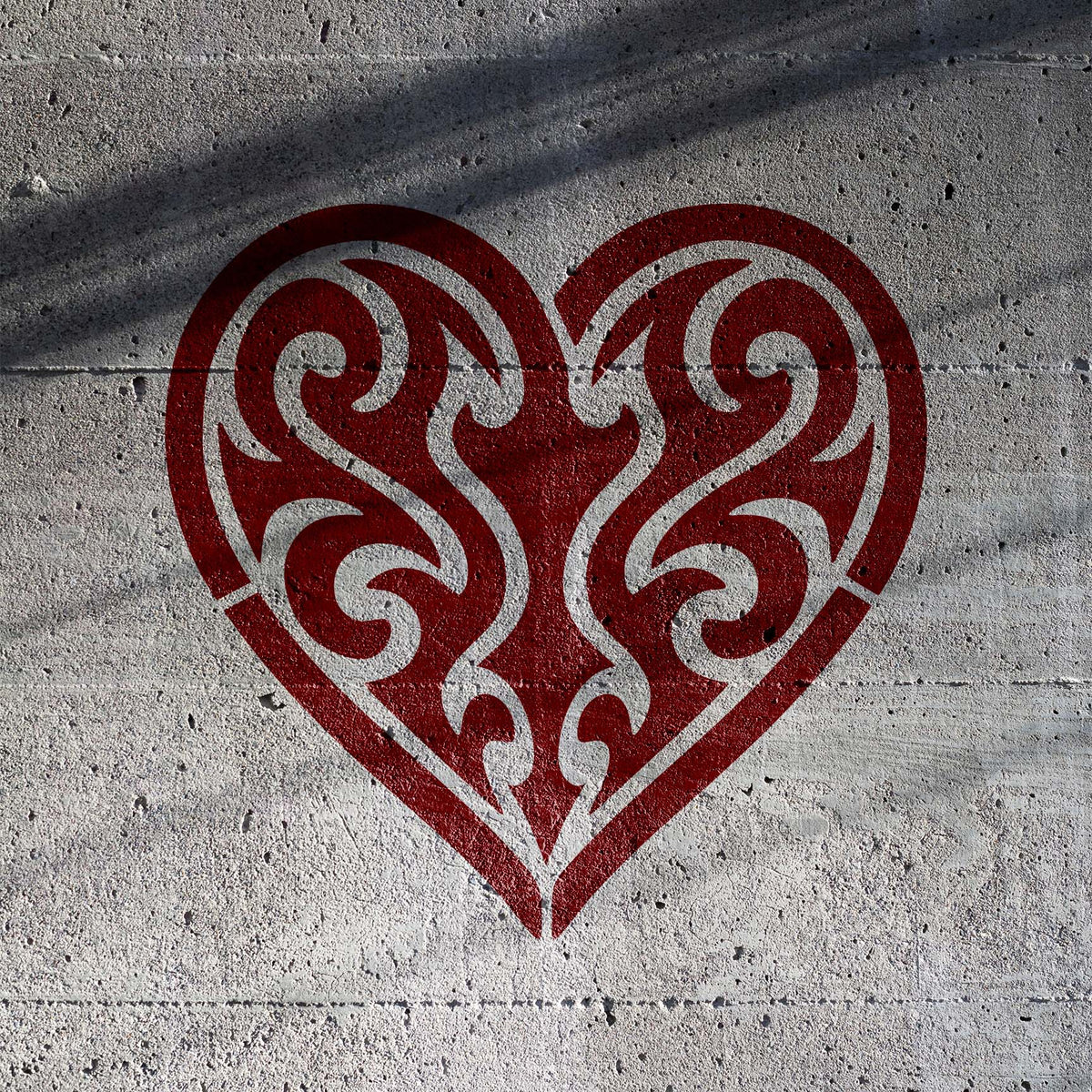 Tribal Heart Stencil adds an intricate red swirling heart design to a textured concrete wall