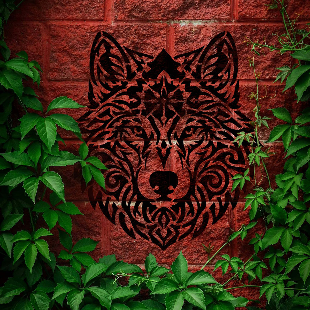Framed by green ivy, the Tribal Mandala Wolf Head Stencil reveals intricate black wolf artwork on red brick.