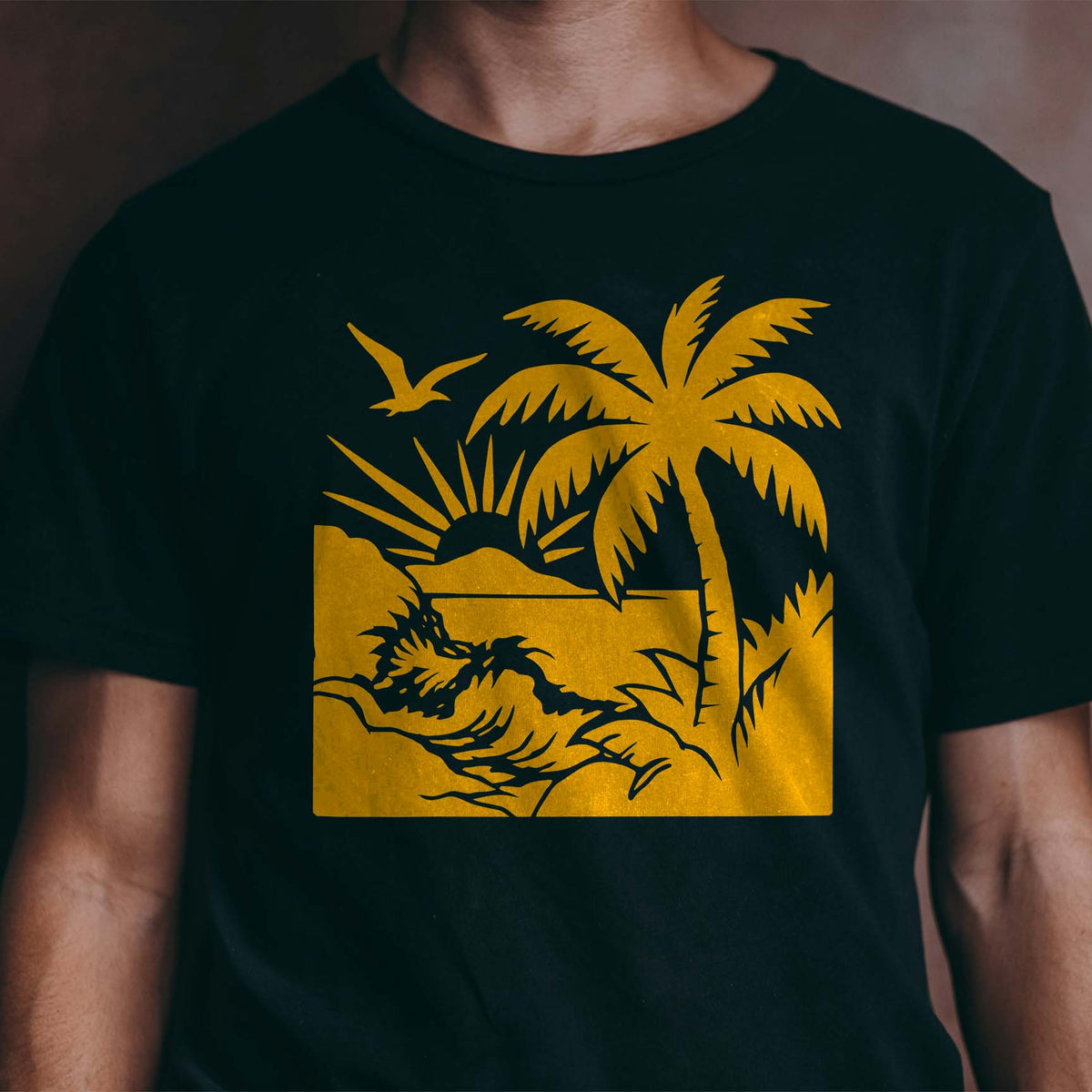 Golden Tropical Beach Sunset Stencil shows a palm, ocean wave, rising sun and soaring bird on a black shirt
