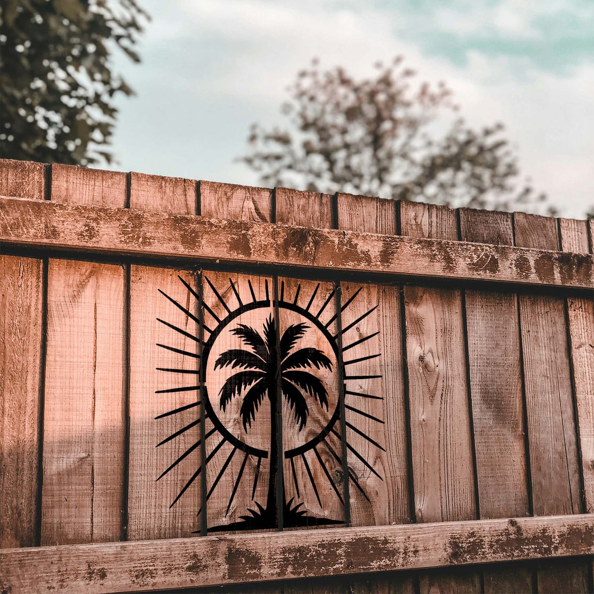 Rustic wood fence features the Tropical Palm Tree Sunburst Stencil in black