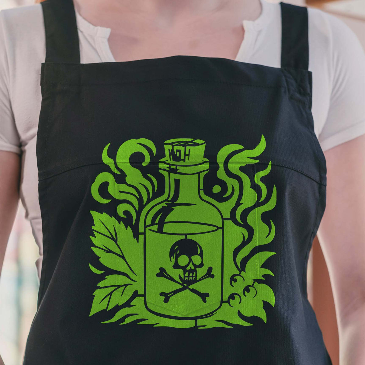 Green Vintage Apothecary Poison Bottle Stencil with skull motif displayed on a black apron
