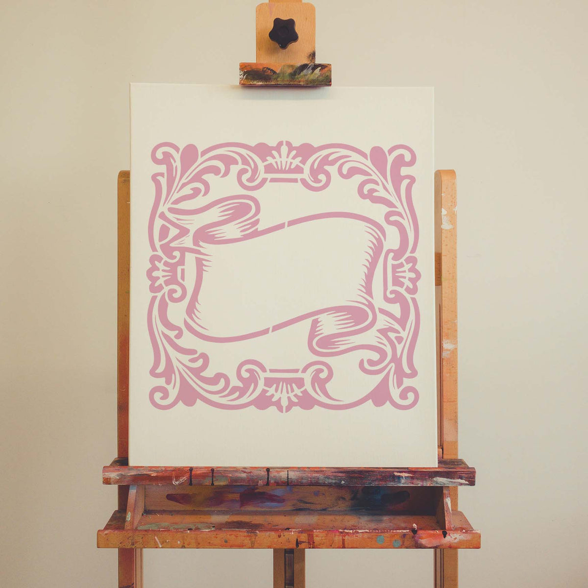 Vintage Scroll Banner Frame stencil displays ornate pink scrollwork on an artist canvas