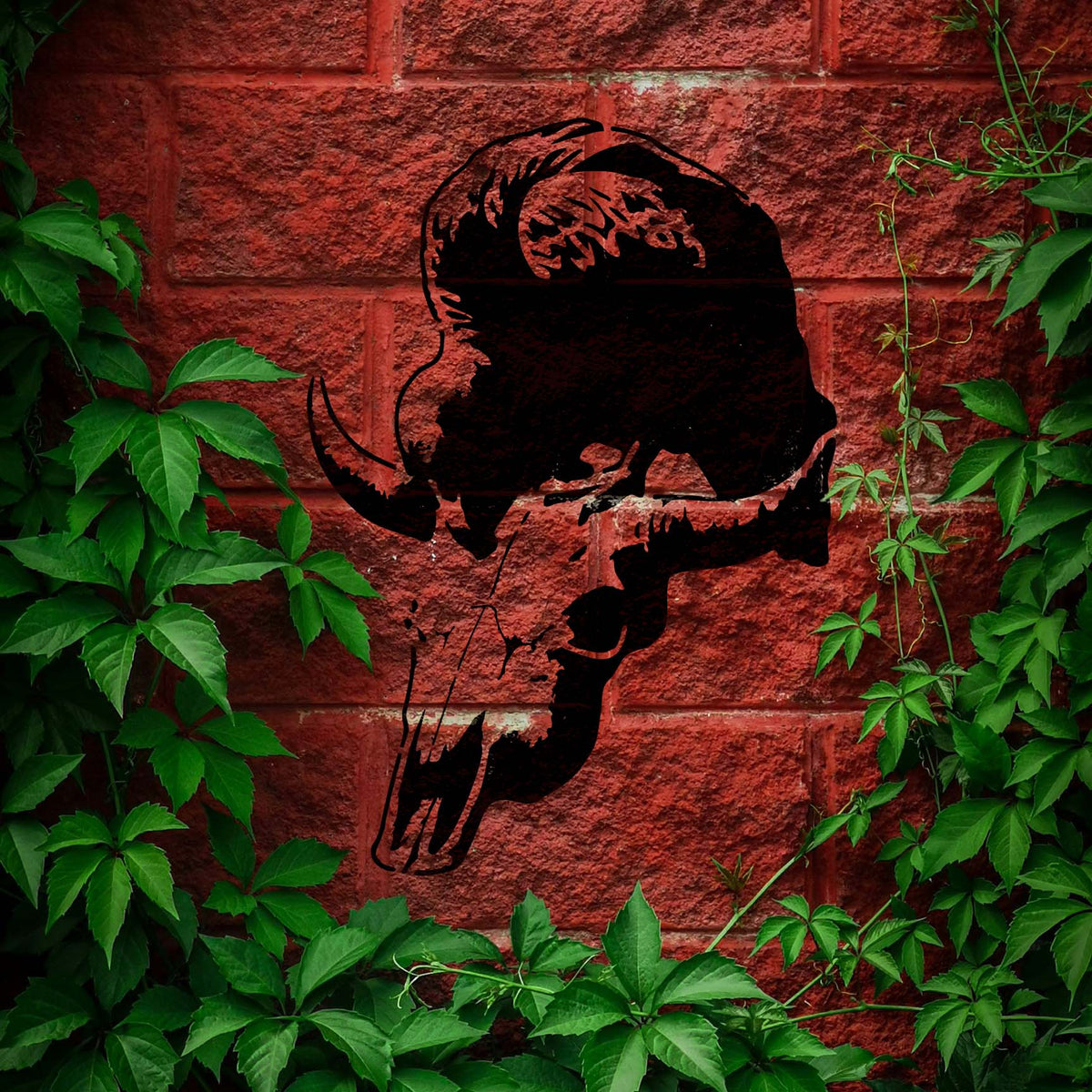 Vulture Skull Silhouette Stencil looms in black across a red brick wall framed by green ivy