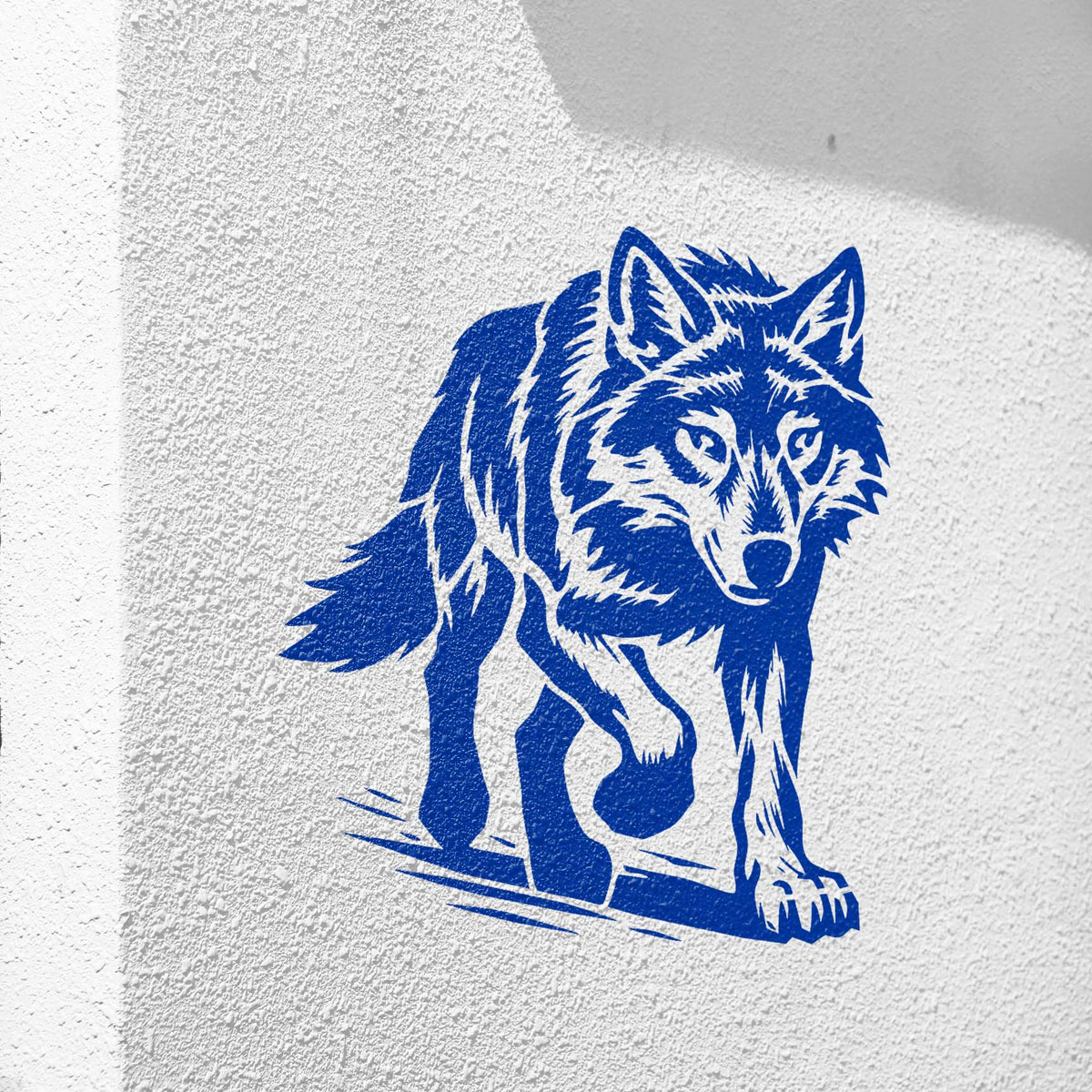 Bold blue Walking Wolf Stencil displayed on a textured white wall with a prowling wolf design.
