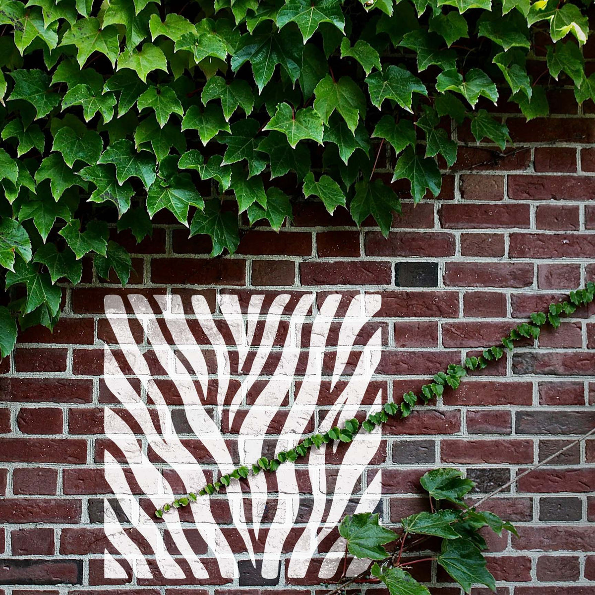 White Wild Tiger Stripes Stencil creates a bold animal pattern across an ivy-covered brick wall