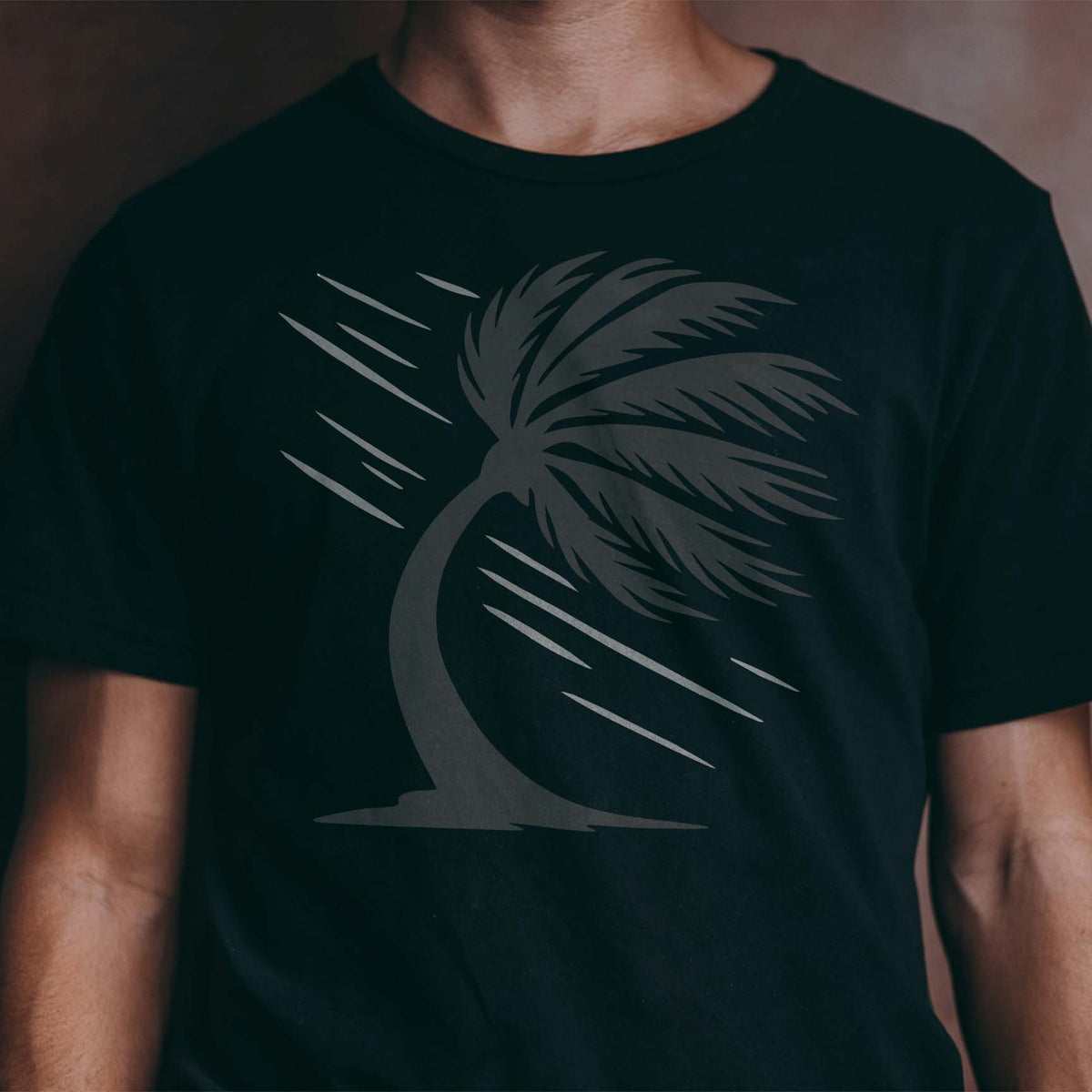 Windblown palm tree stencil with sweeping fronds on a dark shirt