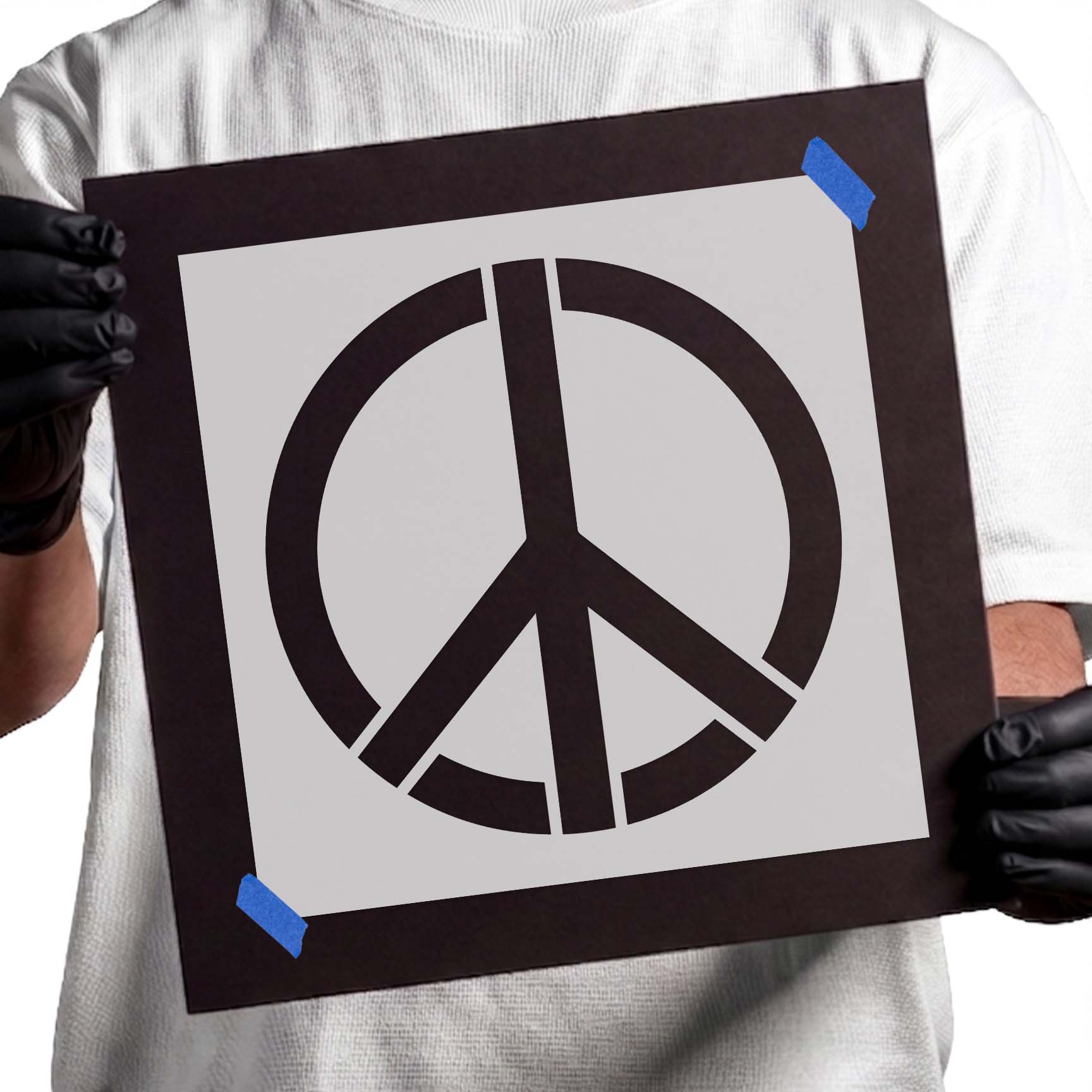Gloved hands holding laser-cut Peace Symbol Stencil