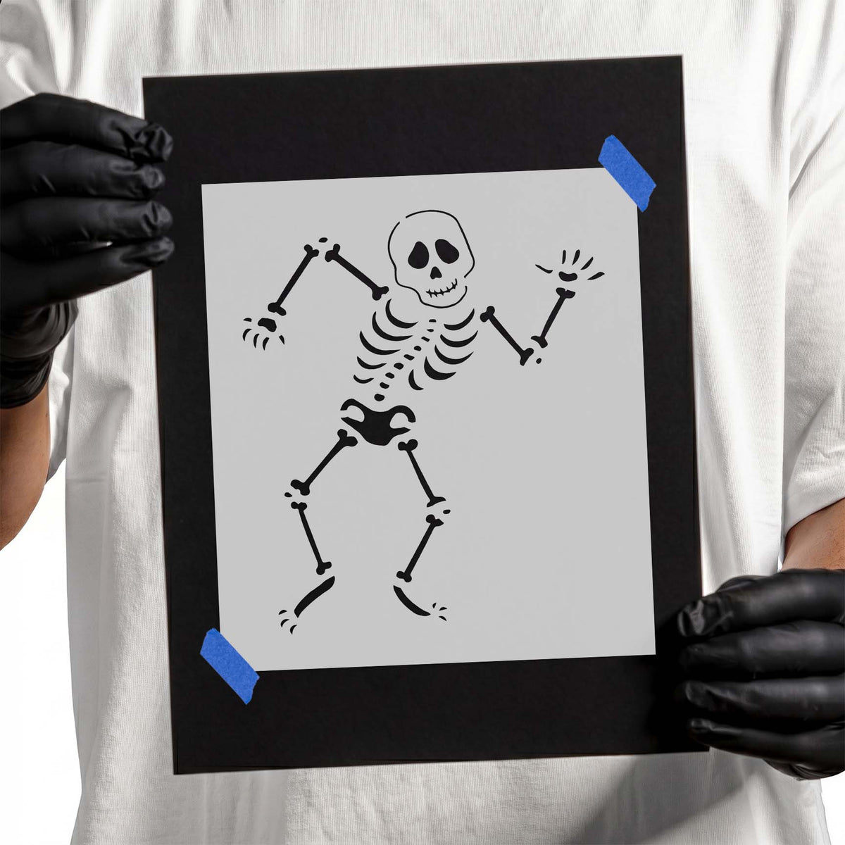 Gloved hands holding laser-cut Silly Skeleton Stencil