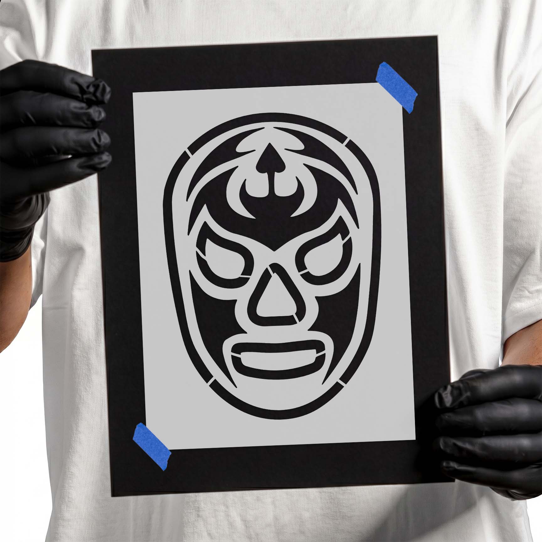 Gloved hands holding a reusable Luchador Mask Stencil