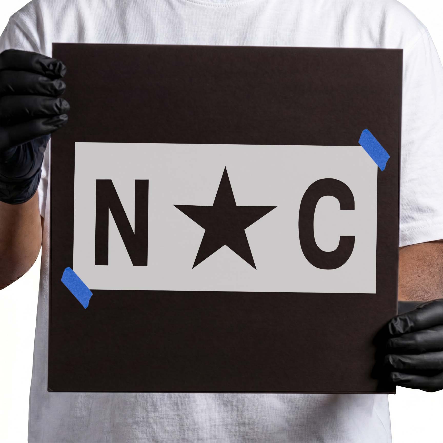 Person holding a North Carolina stencil on a black backing sheet.
