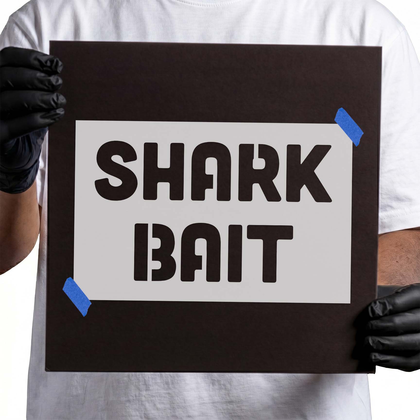 Person holding reusable “Shark Bait” stencil for painting and craft projects.