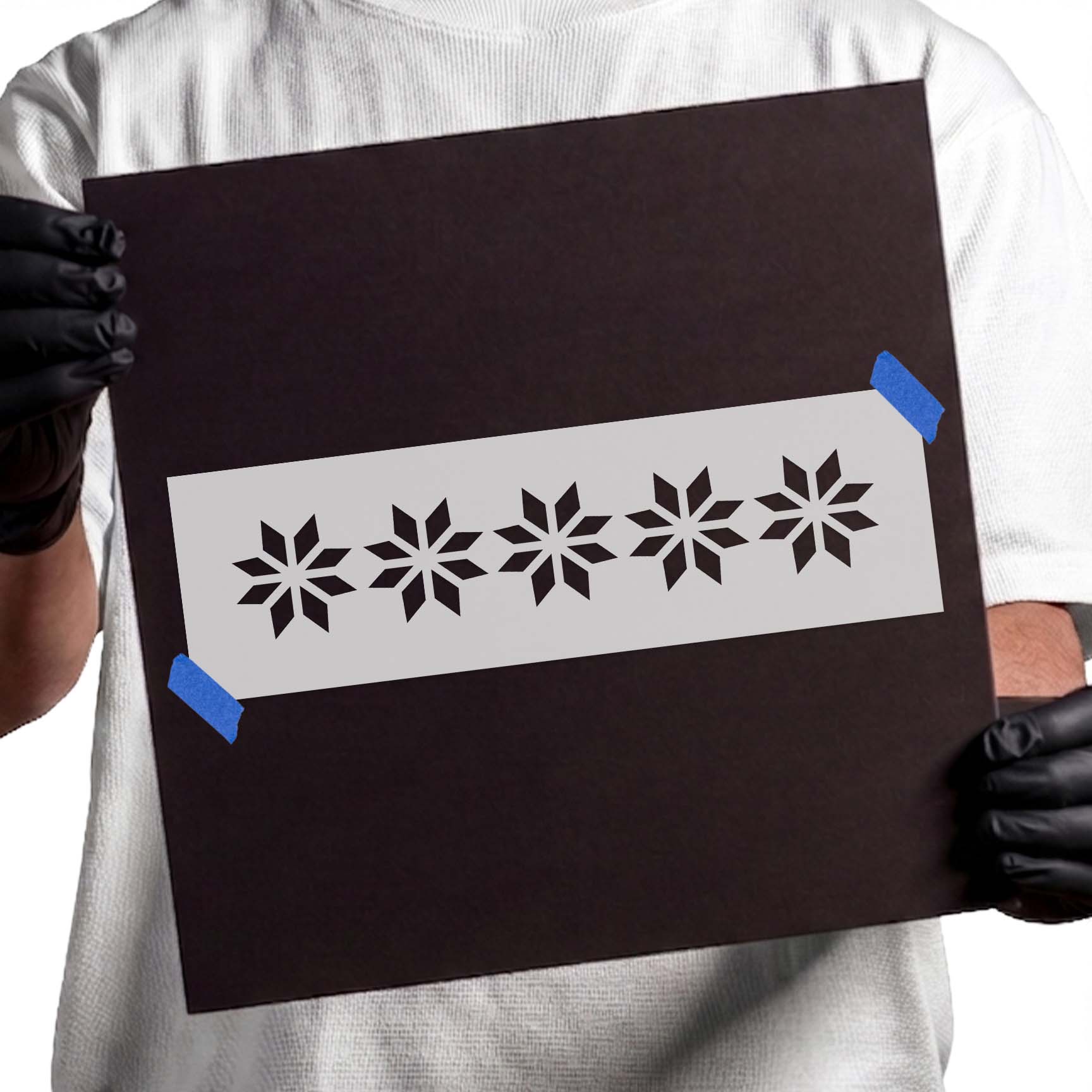 Gloved hands holding a reusable Snowflake Pattern Stencil